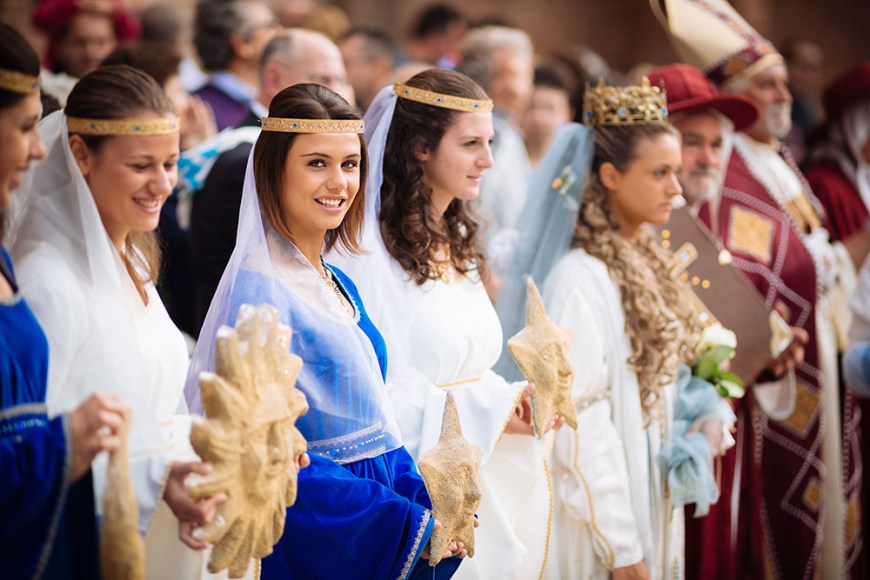 People dressed in traditional medieval costume gather in Piazza Cathedral for a blessing ahead of the Palio di Asti