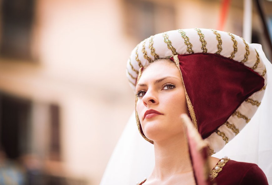 A woman in a medieval costume takes part in a historical parade from the Piazza Cattedrale to the race track ahead of the Palio Di Asti on September 21, 2014 in Asti, Italy
