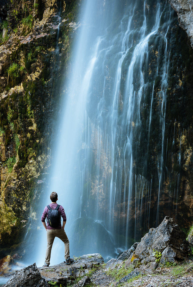 Man looking up at Theth Waterfall, Theth, The Accursed Mountains, Albania