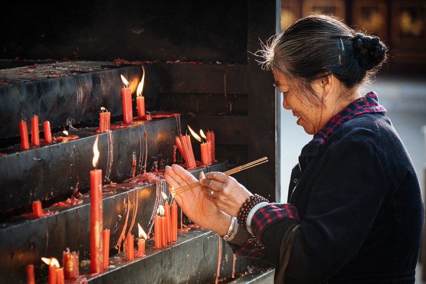 Woman lighting candles at Yuantong Buddhist Temple, Kunming, Yunnan Province, China
