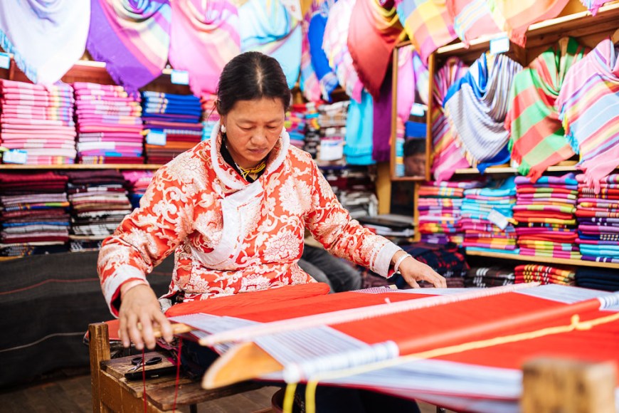 Woman using traditional weaving machine, Lijiang, Yunnan Province, China