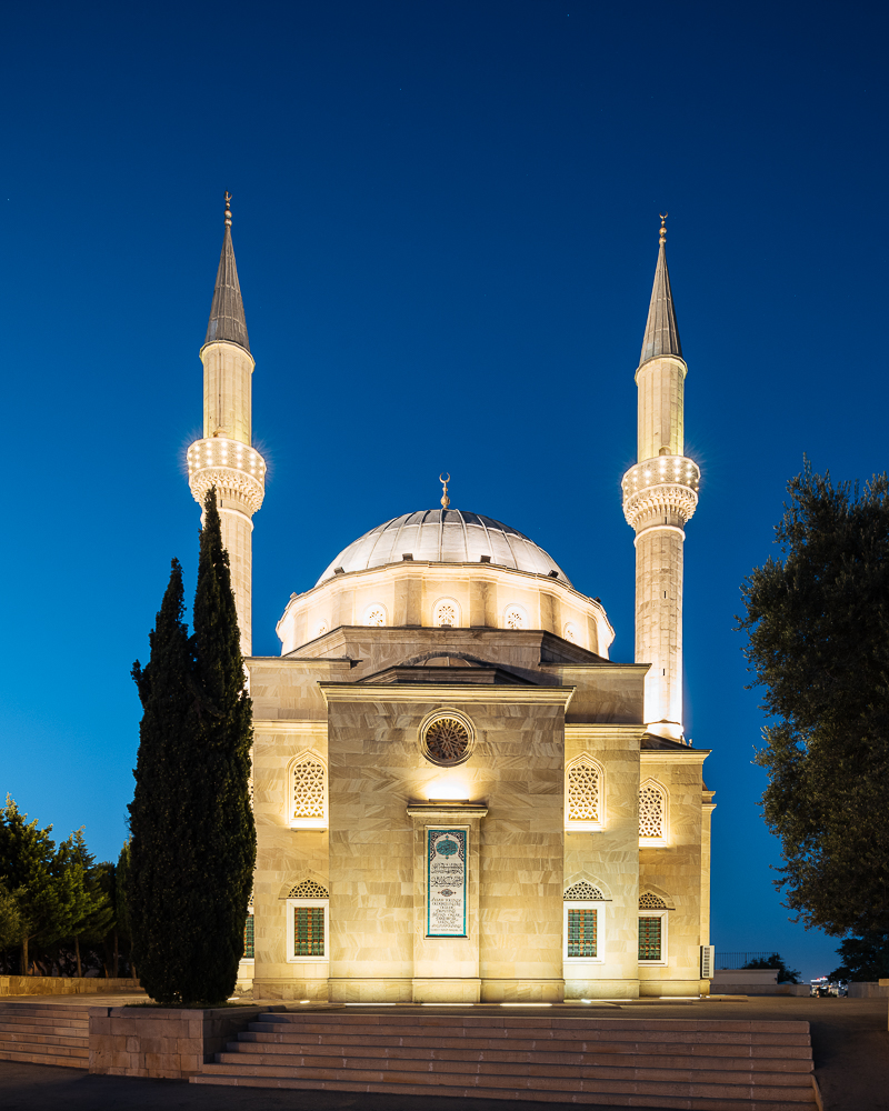 Exterior of The Shahid Mosque with Flame Towers in background at night, Baku, Azerbaijan